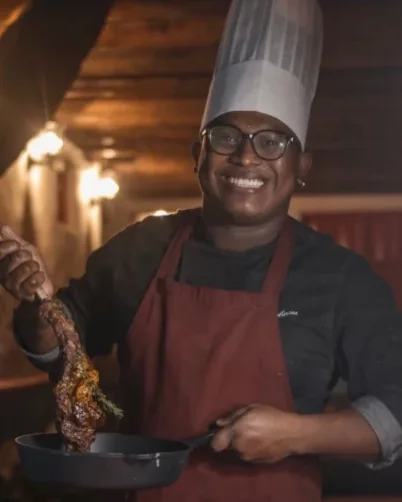 Edd Cabarcas con gorro de chef sirviendo carne desde una sartén de hierro