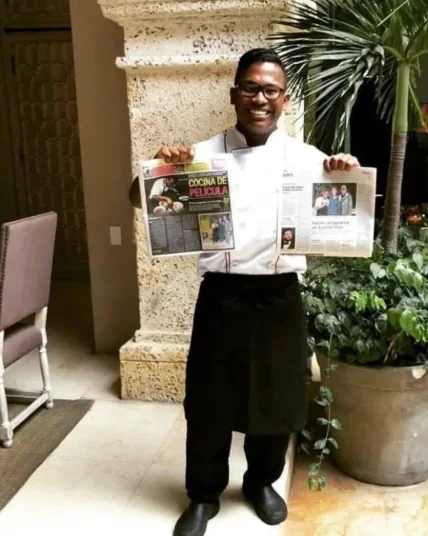 Edd Cabarcas en el patio del hotel mostrando dos periódicos que publicaron su historia