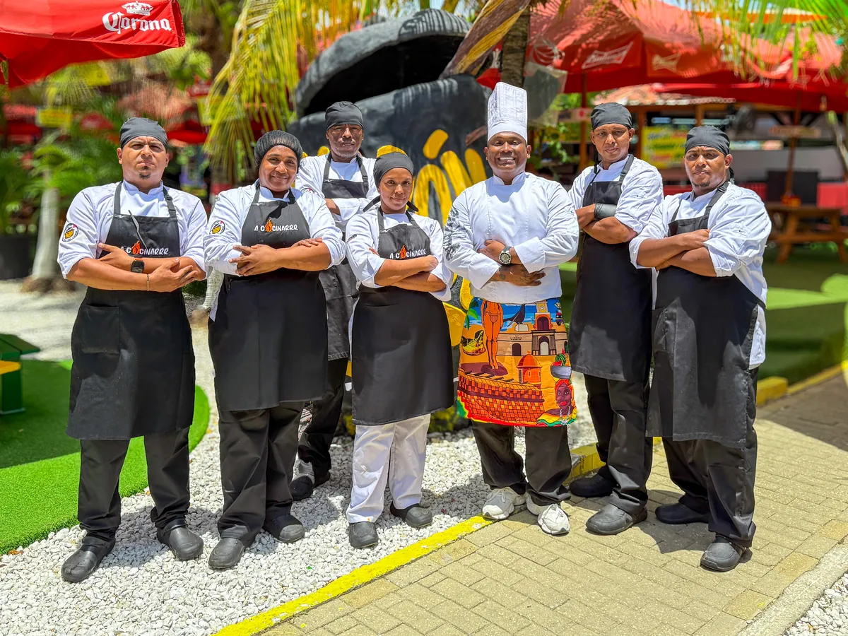 Edd Cabarcas con su equipo de cocina de siete personas, con delantales negros de A Cocinarrr
